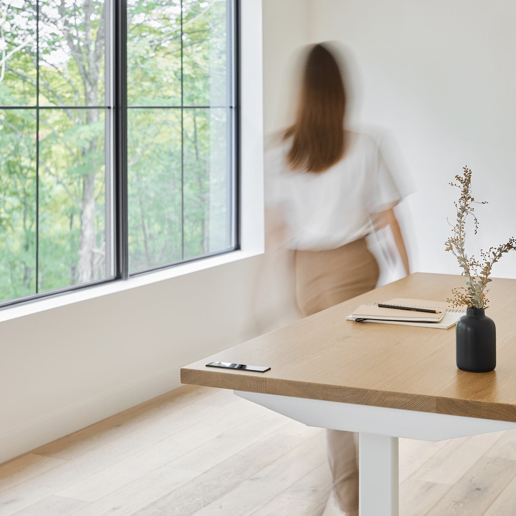 Blurred woman walking past a wooden standing desk