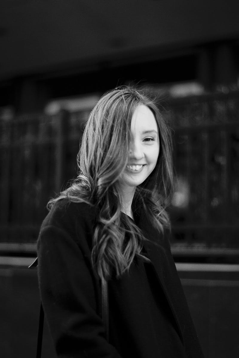 Black and white photo of Jennifer, smiling on a sidewalk